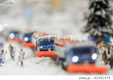 Layout of the city and small figures. Snow-covered road on which snowplows move 92491479