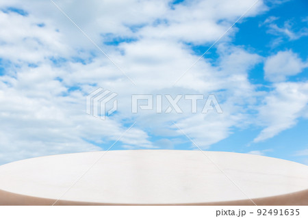 A white marble oval pedestal or table surface on a bright blue cloudy sky background. Copy space. The concept of a product demonstration template A white marble oval pedestal or table surface on a bright blue cloudy sky background. Copy space. The concept of a product demonstration template 92491635