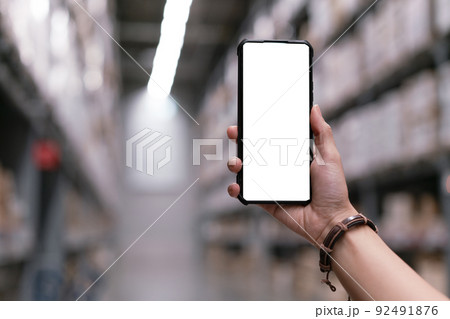 Hand holding smartphone with mock up screen at warehouse. Shopping online concept Hand holding smartphone with mock up screen at warehouse. Shopping online concept 92491876