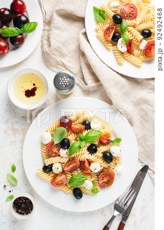 Italian pasta with tomatoes, mozzarella cheese and black olives 92492468