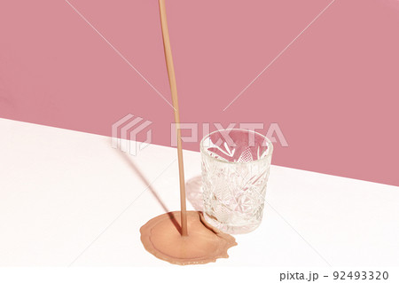 Delicious cocktail, milkshake, spilled on white tablecloth isolated over pink background. Pastel colors 92493320
