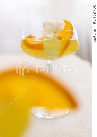 Transparent cocktail with ice cubes in a glass decorated with slices of orange close up Transparent cocktail with ice cubes in a glass decorated with slices of orange close up 92493700
