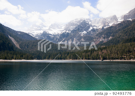 Aerial panoramic view of emerald water of a high-alpine Tovel lake surrounded by wooded and snowy Aerial panoramic view of emerald water of a high-alpine Tovel lake surrounded by wooded and snowy 92493776