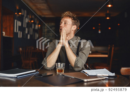 Man drinks whiskey. Businessman reads documents. Director in a shirt and suspenders. Man drinks whiskey. Businessman reads documents. Director in a shirt and suspenders. 92493879