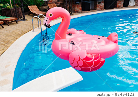 an inflatable flamingo swims in the pool. the concept of summer holidays. an inflatable flamingo swims in the pool. the concept of summer holidays. 92494123