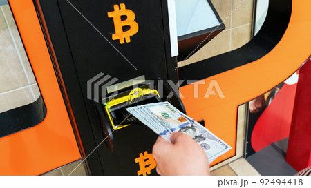 Atm machine bitcoin cryptocurrency. Usd hundred money payment on virtual crypto currency btc wallet. Woman withdraw american dollar bill money. Atm machine finance and technology concept. 92494418