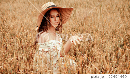 Girl wheat field summer. Happy young woman in sun hat in summer wheat field at sunset. Nature, summer holidays, vacation and people concept. 92494440