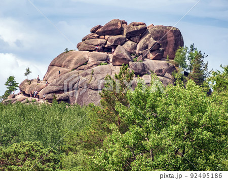 Unrecognizable people are hiking on top of a 300 ft. cliff 92495186