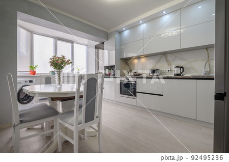 Interior of white modern kitchen with dining table 92495236