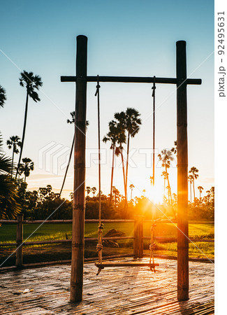 silhouette Empty swings at sunset time on tropical landscape background. 92495631