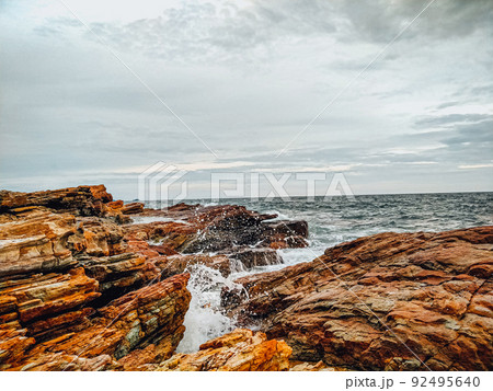 rocky coastline with ocean waves splashing on shore nature landscape background. rocky coastline with ocean waves splashing on shore nature landscape background. 92495640