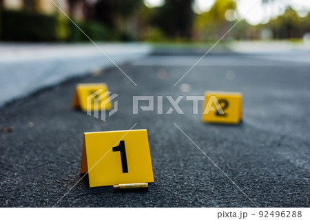 A group of yellow crime scene evidence markers on the street after a gun shooting brass bullet shell casing rifle 92496288