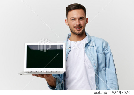 Cheerful friendly tanned handsome IT professional man in casual basic t-shirt with laptop on hand posing isolated on over white studio background. Copy space Banner Mockup. Electronics repair concept Cheerful friendly tanned handsome IT professional man in casual basic t-shirt with laptop on hand posing isolated on over white studio background. Copy space Banner Mockup. Electronics repair concept 92497020