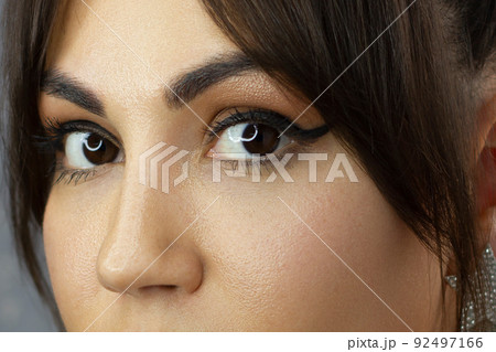 Beautiful macro shot of female eye with classic eyeliner makeup. Perfect shape of eyebrows, brown eyeshadows and long eyelashes. Cosmetics and make-up. Closeup macro shot of fashion liner eyes visage 92497166