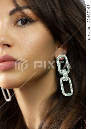 Half a beauty portrait with beautiful fashionable evening make-up, black jiggles on eyes and extremely long eyelashes. Pink lipstick on the lips. Cosmetology and spa facial skin care 92497193