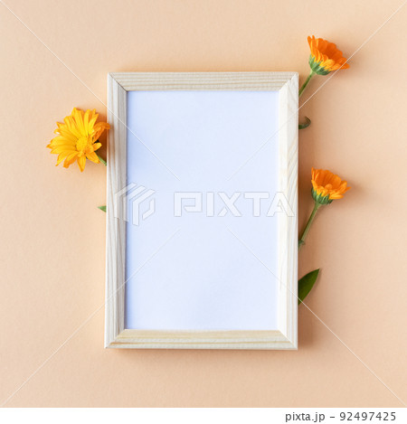 Orange calendula flowers with a white text frame on an orange background. Summer flat lay 92497425