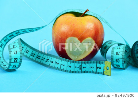 Apple of red color with bitten heart inside near tape Apple of red color with bitten heart inside near tape 92497900