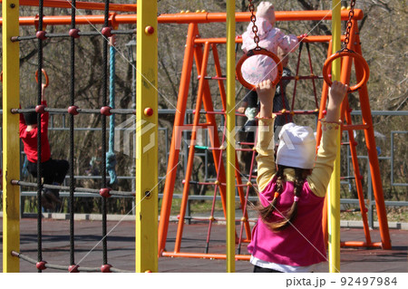 Children on a sunny day play in the playground, equipped with sports equipment.. Children on a sunny day play in the playground, equipped with sports equipment.. 92497984