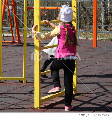 Children on a sunny day play in the playground, equipped with sports equipment.. 92497985