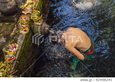 Man in holy spring water temple in bali. The temple compound consists of a petirtaan or bathing structure, famous for its holy spring water 92498291