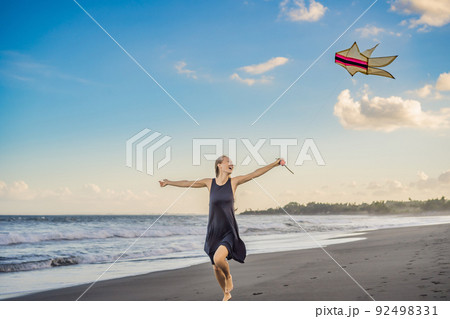 A young woman launches a kite on the beach. Dream, aspirations, future plans 92498331