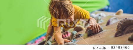 little boy climbing a rock wall in special boots. indoor BANNER, LONG FORMAT little boy climbing a rock wall in special boots. indoor BANNER, LONG FORMAT 92498466