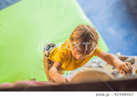 little boy climbing a rock wall in special boots. indoor little boy climbing a rock wall in special boots. indoor 92498467