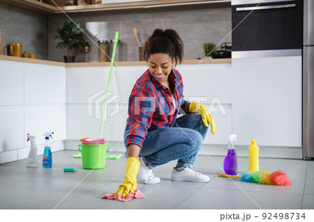 Glad millennial african american woman housewife in rubber gloves wash floor with cleaning supplies 92498734