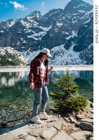 A woman is standing on the shore of a lake. Morskie Oko, Tatras mountains. A woman is standing on the shore of a lake. Morskie Oko, Tatras mountains. 92499432
