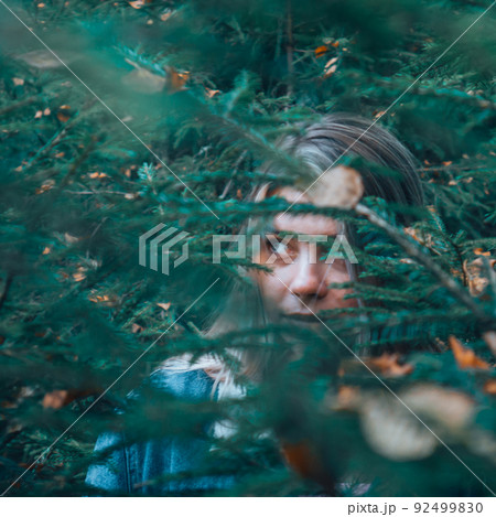 The girls gaze through the foliage in the woods. 92499830