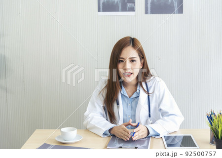Women doctor using laptop tablet telemedicine vdo call conference with patient. women doctor write prescription medical lab working medical clinic looking CAT scan xray film. Women doctor office desk Women doctor using laptop tablet telemedicine vdo call conference with patient. women doctor write prescription medical lab working medical clinic looking CAT scan xray film. Women doctor office desk 92500757