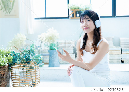 ヘッドフォンでスマホの音楽を聴く若い女性 92503284