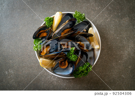 Mussels with herbs in a bowl with lemon 92504306