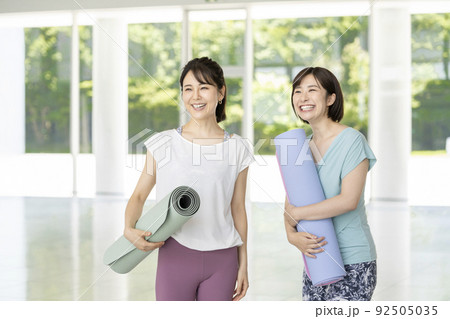 ヨガマットを持った2人の笑顔の若い女性 92505035