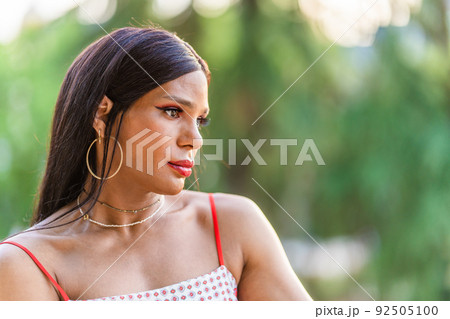 Transgender woman looking aside with worried expression outdoors Transgender woman looking aside with worried expression outdoors 92505100