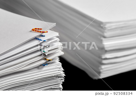 Stacks of papers with multicolored paper clips on a dark background 92508334