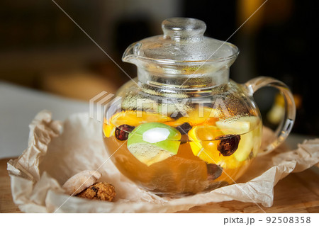 Fruit and berry tea in a transparent glass teapot. Close-up, selective focus 92508358
