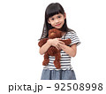 Asian little cute girl smiling and  holding brown bear doll. Preschool lovely kid on white background. 92508998