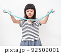 Cute girl 6 year old holding a blue slime and exited. Studio isolated on white background. 92509001