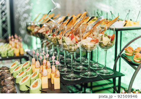 Large table with snacks of different types at a party with creative disco lighting. 92509946