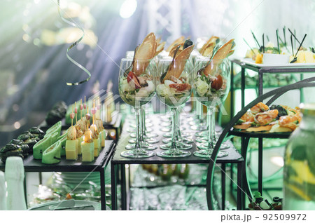 Large table with snacks of different types at a party with creative disco lighting. Large table with snacks of different types at a party with creative disco lighting. 92509972