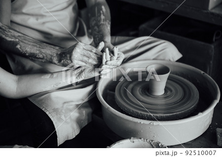 A couple in love creates a joint cup in a pottery workshop. Potter making ceramic pot on the pottery wheel A couple in love creates a joint cup in a pottery workshop. Potter making ceramic pot on the pottery wheel 92510007