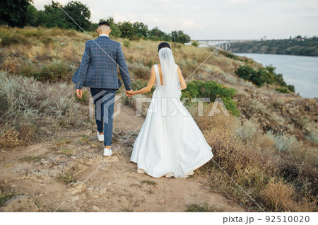 Beautiful wedding bride and groom running in the garden Beautiful wedding bride and groom running in the garden 92510020