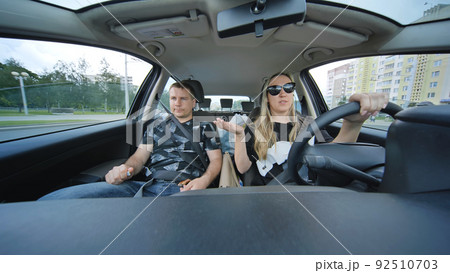 A man and a woman in a car are driving through town. A man and a woman in a car are driving through town. 92510703