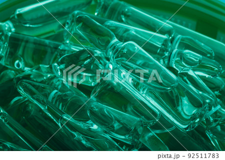 Glass medical ampoule vial for injection. Medicine is liquid sodium chloride with of aqueous solution in ampulla. Close up. Bottles ampule multicolor. 92511783