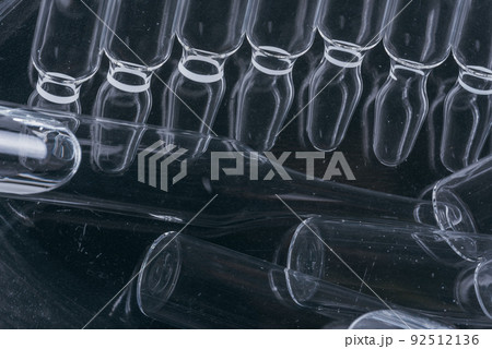 Glass medical ampoule vial for injection. Medicine is liquid sodium chloride with of aqueous solution in ampulla. Close up. Bottles ampule multicolor. 92512136