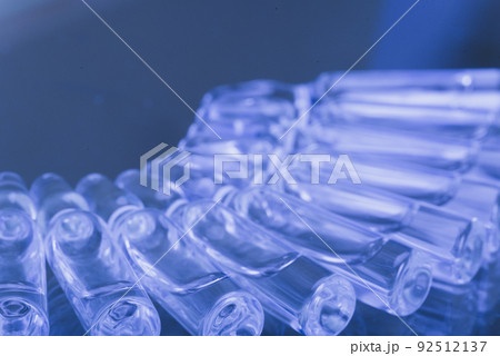 Glass medical ampoule vial for injection. Medicine is liquid sodium chloride with of aqueous solution in ampulla. Close up. Bottles ampule multicolor. 92512137