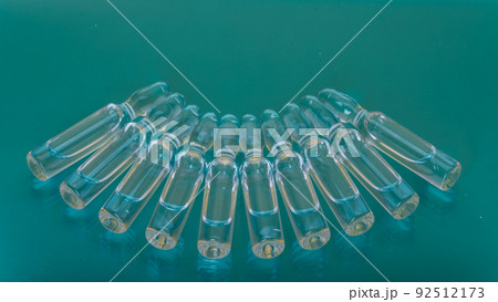 Glass medical ampoule vial for injection. Medicine is liquid sodium chloride with of aqueous solution in ampulla. Close up. Bottles ampule multicolor. 92512173