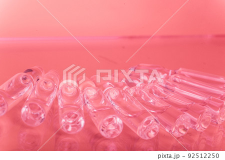 Glass medical ampoule vial for injection. Medicine is liquid sodium chloride with of aqueous solution in ampulla. Close up. Bottles ampule multicolor. 92512250