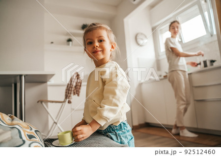 Female child and her parent in the kitchen Female child and her parent in the kitchen 92512460